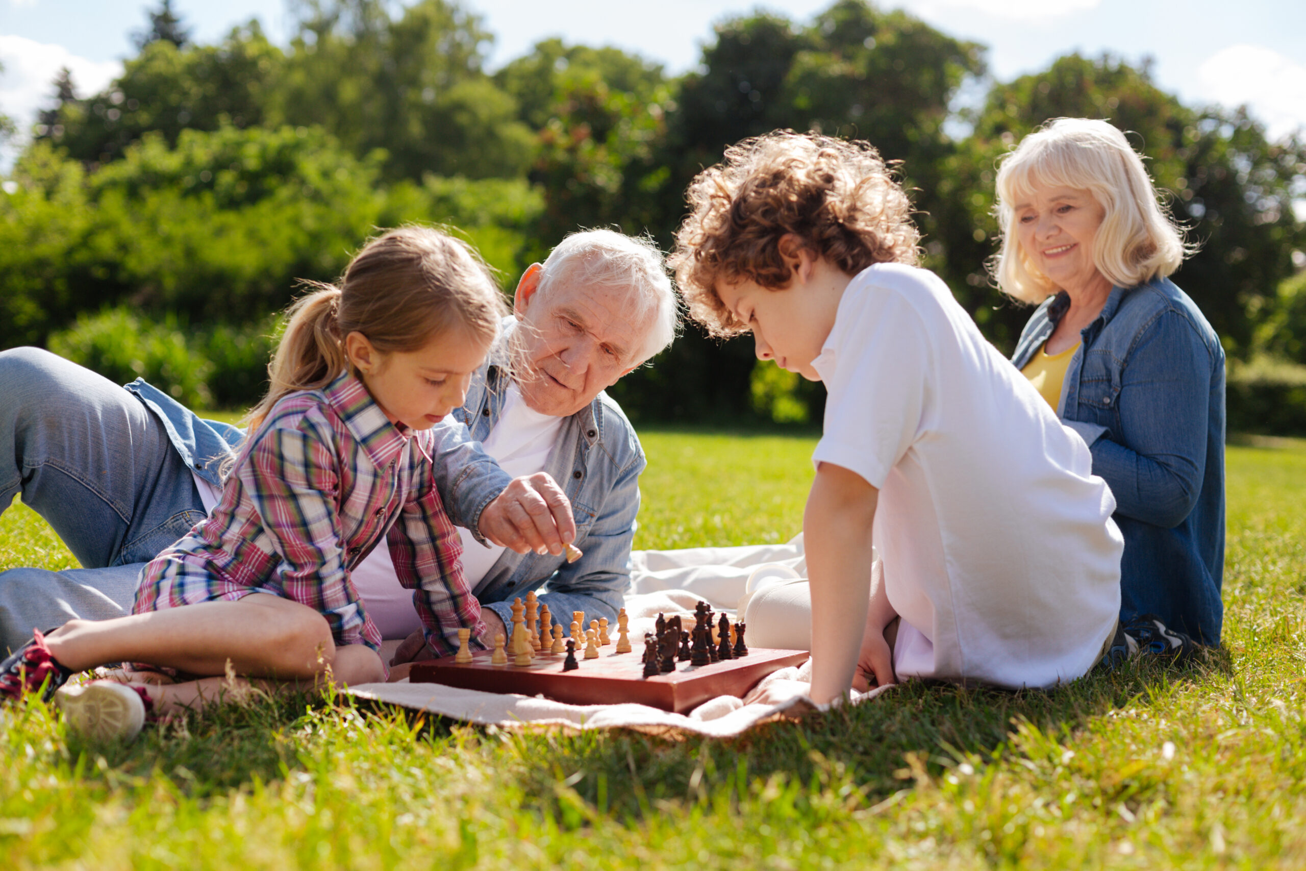 Kind grandpa helping his granddaughter play chess