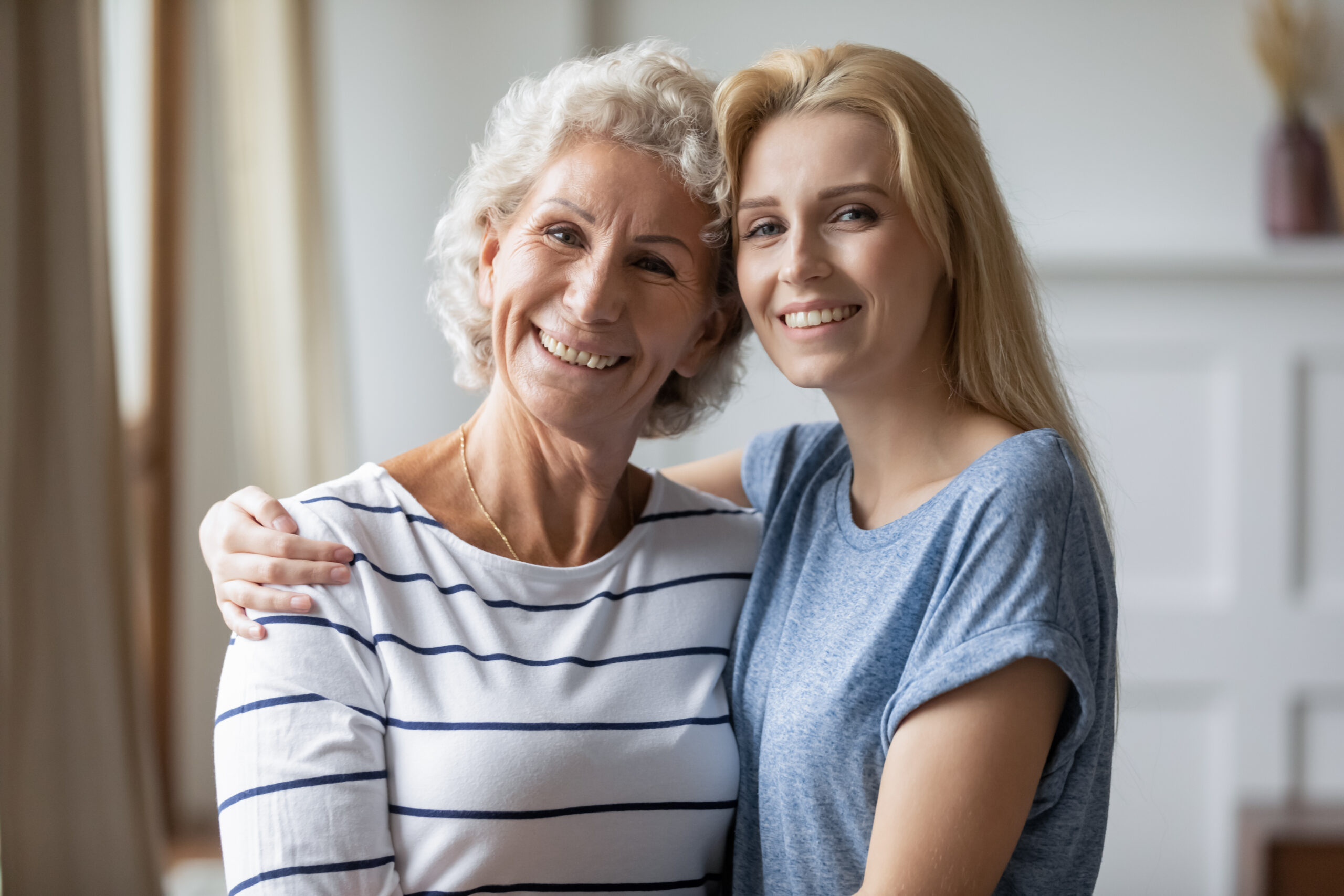 Portrait of happy mature mom and adult daughter hugging